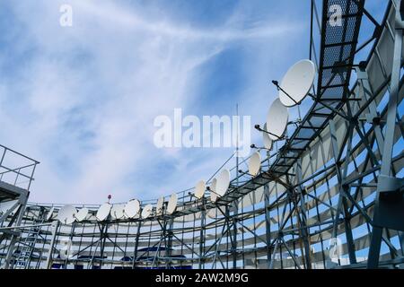 Satellitenantennen befinden sich auf dem Dach des Gebäudes. TV-Sender mit vielen Empfangsgeräten. Telekommunikationsausrüstung des Telekommunikationsgeräts Stockfoto