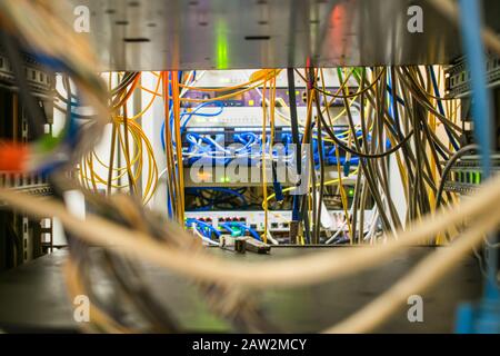 Viele Kabel befinden sich im Rack mit den Schaltgeräten des Internetanbieters. Die Kommunikationskabel und LWL-Patchkabel befinden sich in Stockfoto