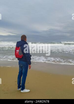 27. Januar 2020, Porto, Portugal: Ein Mann in einer blauen Jacke mit rotem Rucksack steht an einem bewölkten Tag am Ufer des Atlantiks. (Bild: © Igor Golovniov/SOPA Bilder über ZUMA Draht) Stockfoto