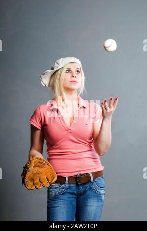 Blondes Mädchen in Baseballmütze mit Schlaghandschuh und Baseball Stockfoto