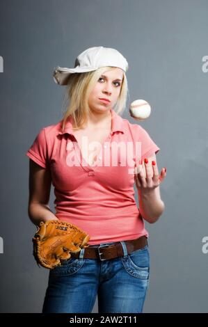 Blondes Mädchen in Baseballmütze mit Schlaghandschuh und Baseball Stockfoto