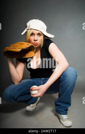 Blondes Mädchen in Baseballmütze mit Schlaghandschuh und Baseball Stockfoto