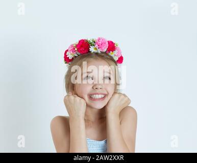 Fröhliches Kindermädchen jubelt, feiert und pumpt Fäuste, die glücklich auf den Kopierraum schauen. Nahaufnahme des kaukasischen Kindermodells mit Blumen-HE Stockfoto