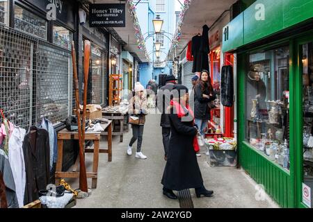 Käufer, die in den Antiquitätengeschäften und Verkaufsständen in Pierrepont Row, abseits Der Camden Passage at The Angel, Islington, London, Großbritannien stöbern Stockfoto