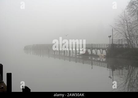 Blick auf einen Gehweg über teddington Weir an einem nebligen Tag im Winter Stockfoto