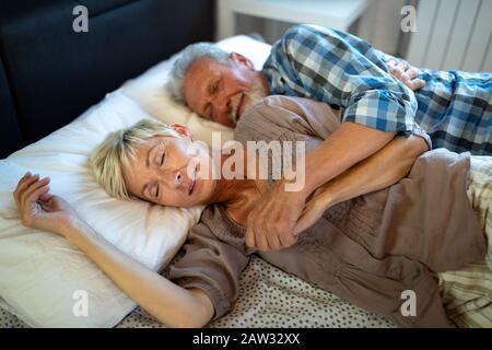 Schönes älteres Paar liegend, schlafen auf dem Bett zusammen Stockfoto