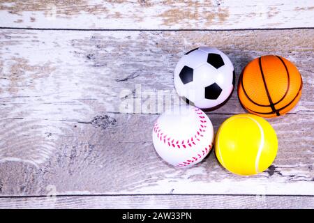 Eine Nahaufnahme Bild aus einem Stapel von Sport Bälle gegen eine reflektierende blauen Hintergrund. In der Stapel ist ein Fußball, Baseball, Basketball und Tennis ball. Stockfoto