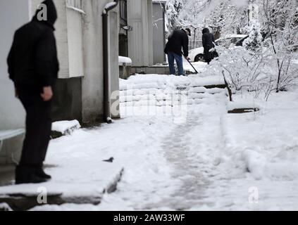 Die Leute gehen auf einem unverputzten Gehweg, auf einem glatten und eisigen Gehweg. Stockfoto