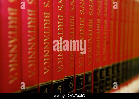 Eine Reihe von roten Lexikonbüchern auf einem Regal in einer Schulbibliothek Stockfoto