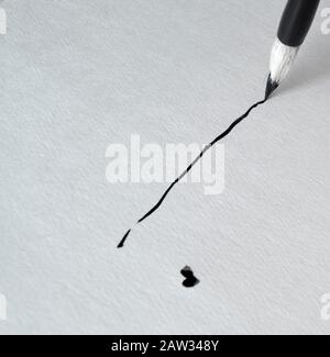 Die Linie wird mit schwarzer Tinte und einem Pinsel für Kalligraphie gezeichnet Stockfoto