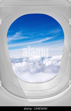 Blick durch Flugzeugfenster, Himmel über den Wolken Stockfoto