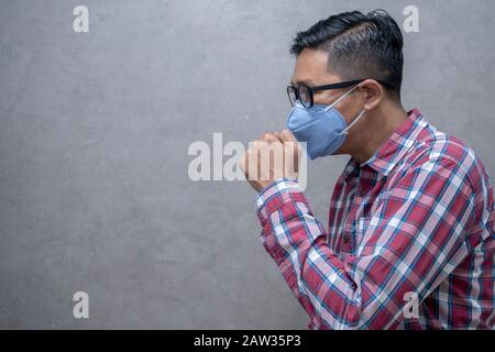 Studio-Bild von einem jungen Mann mit Maske. Der isolierte Kranke hat eine laufende Nase.Nerd trägt eine Brille. Stockfoto
