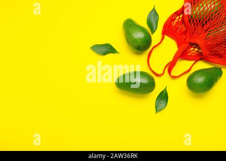 Avocados Früchte in roter wiederverwendbarer Öko Tasche aus Mesh. Recycelter Netzbeutel für Obst und Gemüse. Kunststofffreies, Entsorgungskonzept. Minimale flache Lage Stockfoto