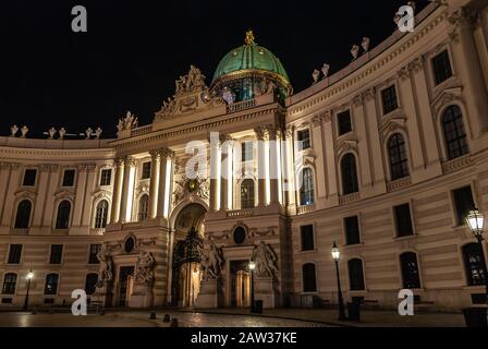 Wien, Österreich. Hauptzugang zum Schloss Hofburg, nachts vom Michaelerplatz aus gesehen, Weitblick in der Abenddämmerung, Wahrzeichen des Habsburger Imperiums in Wien