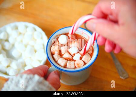 Eine Frau mit einer Tasse heißen Kakao, Marshmallows und eine Zuckerstange Stockfoto