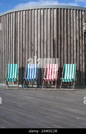 Vier farbenfrohe, gestreifte Liegestühle, Großbritannien Stockfoto