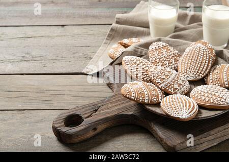 Schöne osterkekse auf einem Teller, ein Glas Milch. Auf altem Holzhintergrund Stockfoto