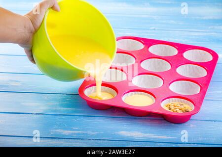 Kuchen in Silikonform auf blauem rustikalem Holzhintergrund gießen. Stockfoto