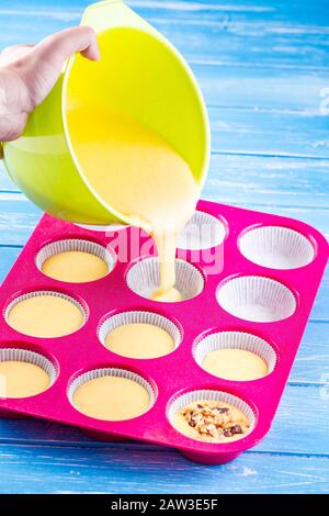 Kuchen in Silikonform auf blauem rustikalem Holzhintergrund gießen. Stockfoto