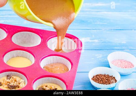 Kuchen in Silikonform auf blauem rustikalem Holzhintergrund gießen. Stockfoto