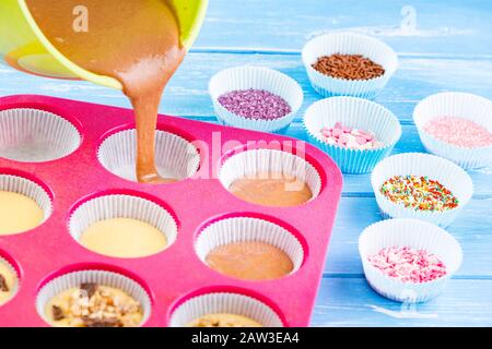 Kuchen in Silikonform auf blauem rustikalem Holzhintergrund gießen. Stockfoto