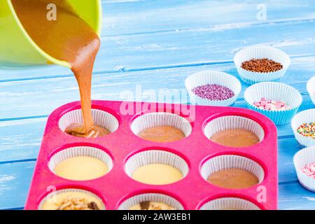 Kuchen in Silikonform auf blauem rustikalem Holzhintergrund gießen. Stockfoto