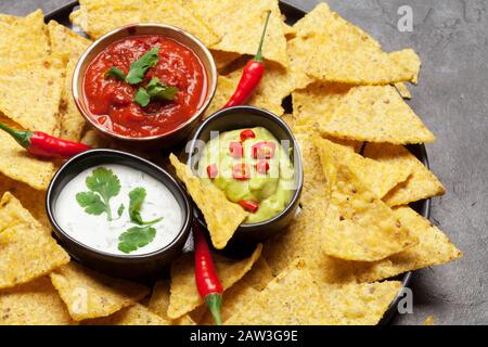 Mexikanische Nachos Chips mit verschiedenen Soßen - Guacamol, Salsa und Sauerrahm Stockfoto