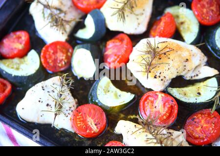 Ansicht von oben Huhn ohne Knochen, Zucchini und Tomaten auf Backblech Stockfoto