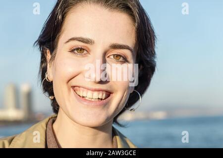 Portrait eines jungen, lieblichen Mädchens mit kurzen Haaren und schönen grünen Augen, die vor einem blauen Himmelshintergrund lächeln, Konzept von Schönheit, Jugend und Taucher Stockfoto