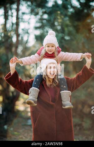 Mutter und Tochter spielen, Spaß haben und fröhlich lachen, während sie im Wald spazieren. Stockfoto