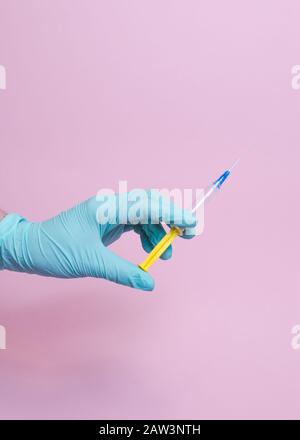 Nahaufnahme der Handspritze des weiblichen Arztes mit Impfstoff. Konzepte für die Sicherheit und das Gesundheitswesen der Medizin. Isoliert auf pinkfarbenem Hintergrund. Kopierbereich. Stockfoto