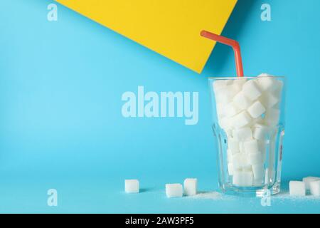 Glas mit Zuckerwürfeln und Strohhalm auf zweifarbiges Hintergrundbild, Platz für Text Stockfoto