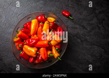 Bunte Mini-Paprika in Glasschale auf dunklem Hintergrund, Draufsicht Stockfoto