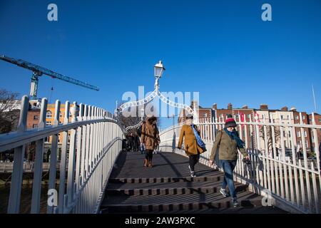 Dublin, Irland - 29. Januar 2020: Menschen, die die ha'Penny Bridge im Stadtzentrum von Dublin überqueren Stockfoto