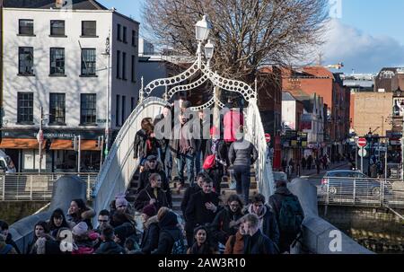 Dublin, Irland - 29. Januar 2020: Fußgänger, die die Straße durch die ha'Penny Bridge im Stadtzentrum von Dublin überqueren, Stockfoto