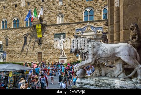 Flaminio Vacca's Medici-Löwe in der Lomia dei Lanzi vor dem Hintergrund der Replikatstatue von Michelangelos David, Piazza della Signoria, Florenz, T Stockfoto