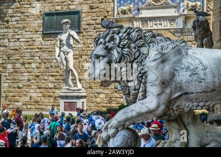 Flaminio Vacca's Medici-Löwe in der Lomia dei Lanzi vor dem Hintergrund der Replikatstatue von Michelangelos David, Piazza della Signoria, Florenz, T Stockfoto