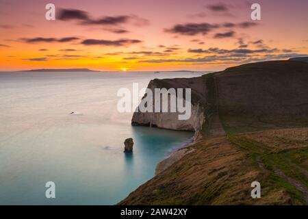 Lulworth, Dorset, Großbritannien. Februar 2020. Wetter in Großbritannien. Ein goldener Sonnenuntergang bei Bats Head in der Nähe von Lulworth in Dorset mit Blick nach Westen in Richtung Weymouth und auf die Insel Portland, vom South West Coast Path auf Swyre Head aus gesehen. Bildnachweis: Graham Hunt/Alamy Live News Stockfoto