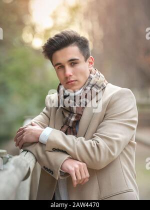 Porträt eines jungen Kerls auf der Straße in Mantel und Schal. Stockfoto