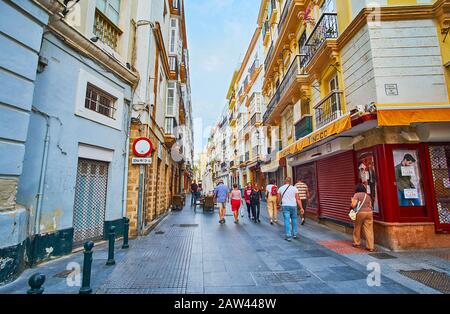 Cadiz, SPANIEN - 20. SEPTEMBER 2019: Die enge Straße Calle Marques de Cádiz ist von historischen Baustellen gesäumt, die mit Geschäften, Geschäften und Cafés besetzt sind Stockfoto