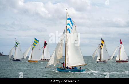 Bunte Gruppe von Falmouth Arbeitsbooten in voller Höhe segeln in der Falmouth-Flussmünde in einer brishen Brise, Sonne und Wolke aus, einzigartige topsegelfarben fliegen Stockfoto