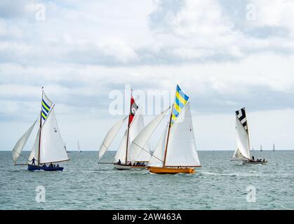 Bunte Gruppe von Falmouth Arbeitsbooten in voller Höhe segeln in der Falmouth-Flussmünde in einer brishen Brise, Sonne und Wolke aus, einzigartige topsegelfarben fliegen Stockfoto