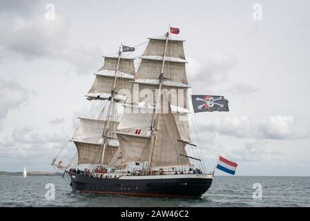 Der riesige fünf Tropfen segelte, zweimastiges Schiff der Mercedes, der die Jolly Roger-, Schädel- und Kreuzbeinfahne in einer steifen Brise vor Falmouth flog. Stockfoto