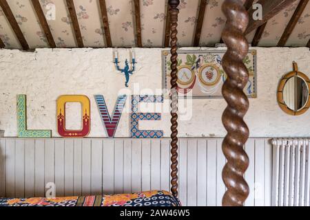 Farbenfrohes "Love"-Zeichen im rustikalen Schlafzimmer Stockfoto