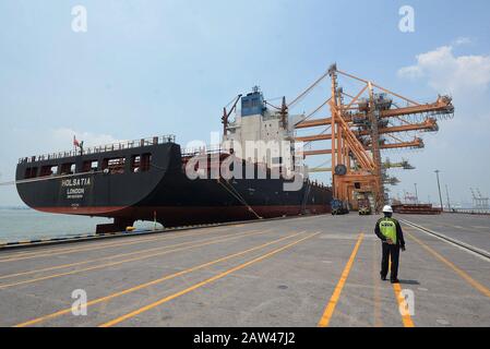 Die Arbeiter führen am 6. April 2019 Containerladen und Entladeaktivitäten vom Schiff MV Holsatia (Großbritannien) bis 699 980 (Liegeplatz 04) im Internationalen Hafen von PT Surabaya Petikemas Terminal (TPS), Surabaya, East Java, Indonesien durch. PT Terminal Petikemas Surabaya beginnt, die Lade- und Entladedienste auf einem Schiff zu erhöhen, das zuvor nur 1.700 bis 2.000 Kisten oder 2.700 TEUs gemittelt hatte. Derzeit ist TPS in der Lage, Schiffe mit der größten Ladung von über 3.100 Containern oder rund 4.600 TEUs für den Handel in ganz Asien zu bedienen. Stockfoto