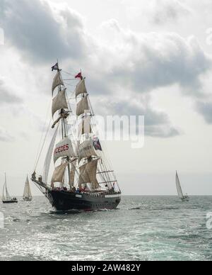 Der massive große, zweiteilige Mast, Schiff der Mercedes, segelt mit Wind, der die Piratenfahne von Jolly Roger als Teil des Großen Schiffsrennens flog. Stockfoto