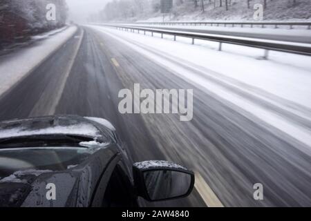 Außenbewegungsunschärfe Aufnahme von Autoüberdrehungen entlang schneebedeckter zweispurigen Fahrbahnen Stockfoto