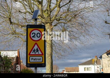 Ein Schild mit 20 MPH oder 20 mph und Patrouille vor einem Schultore Stockfoto