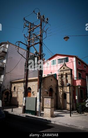 Eine kleine Kirche im Zentrum von zakynthos, die in einer Seitenstraße versteckt ist, liegt zwischen einer großen elektrischen Umspannstation und einem Gebäude. Stockfoto