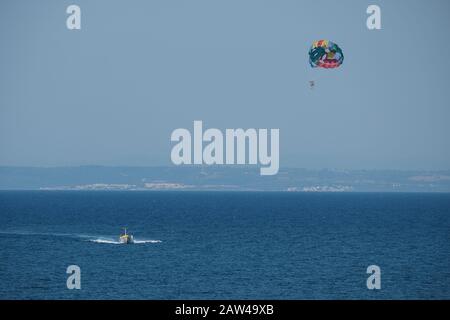 Ein Paar wird auf eine Thrillerfahrt genommen, während sie über dem Meer in Zakynthos Griechenland parasitieren. Stockfoto